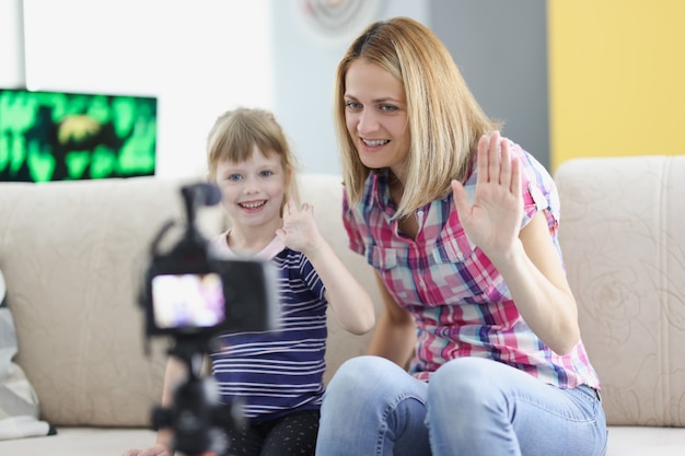 Moeder en dochter nemen een videogroet op camera op. Familie videoblog. Moeder deelt haar ervaring met het opvoeden van een kind