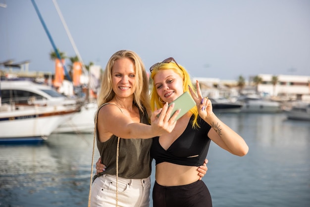 Moeder en dochter nemen selfies tegen de achtergrond van de zee en jachten