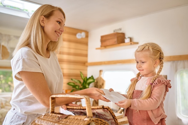 Moeder en dochter op de keuken in trailer, zomerkamperen. Echtpaar met kinderen reizen in kamp auto, camper interieur op achtergrond. Campingavontuur, reizende levensstijl, vakantie met een camper