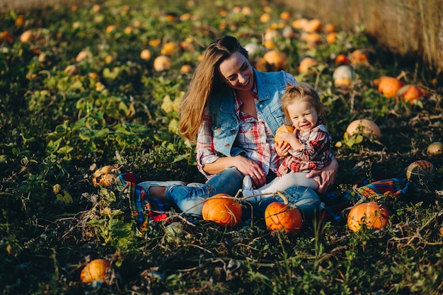 Moeder en dochter op een veld met pompoenen, Halloween vooravond