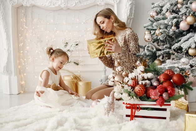 Moeder en dochter openen samen een cadeau bij de kerstboom