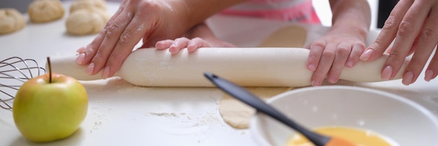 Moeder en dochter rollen meeldeeg uit aan tafel close-up