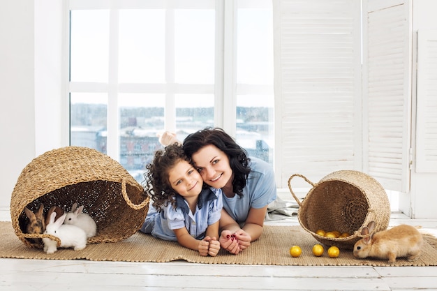 Moeder en dochter schattig mooi en blij met konijnen en paaseieren samen in rieten manden