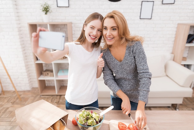 Moeder en dochter selfie nemen in de keuken.