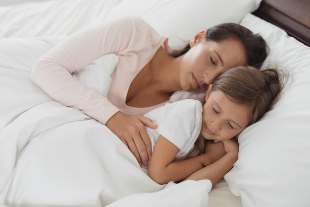 Moeder en dochter slapen op bed in de slaapkamer.