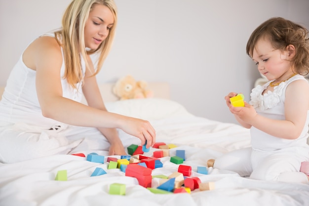 Moeder en dochter spelen met bouwstenen op bed