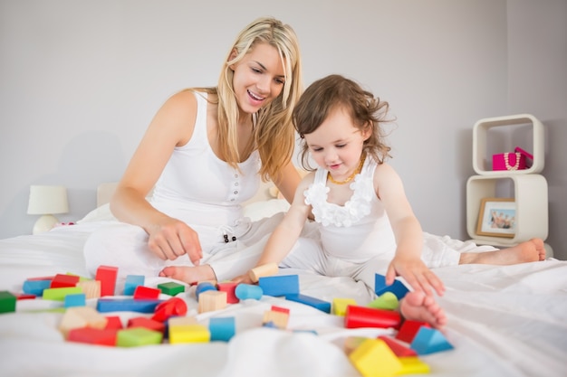 Moeder en dochter spelen met bouwstenen op bed