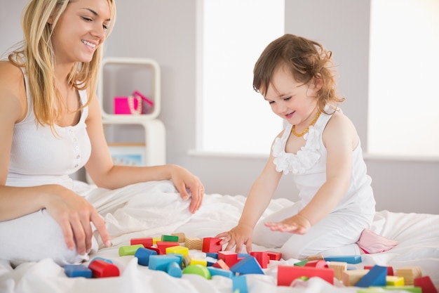 Moeder en dochter spelen met bouwstenen op bed