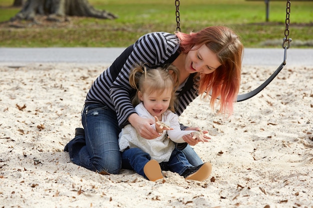 Moeder en dochter spelen met zand in park