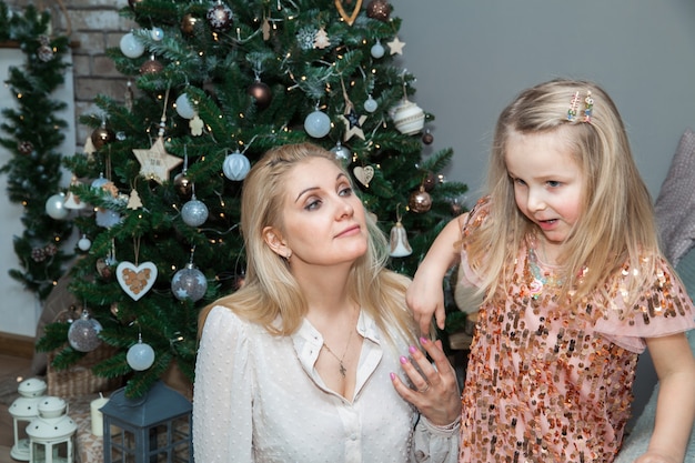 Moeder en dochter versieren de boom in de kamer. Liefdevolle familie binnenshuis. Prettige kerstdagen en fijne feestdagen