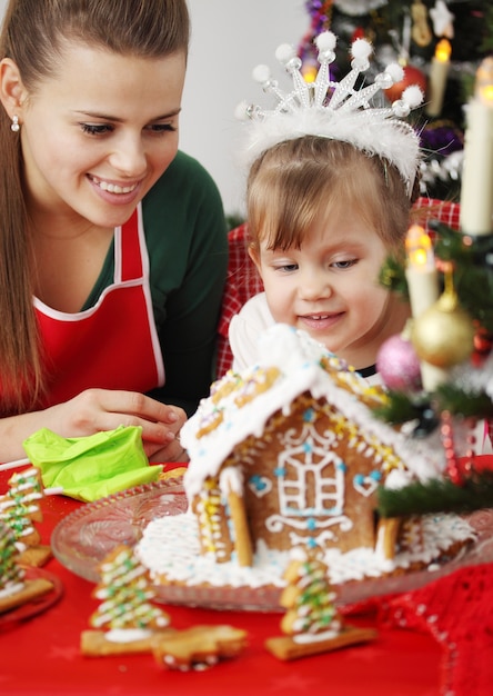 Moeder en dochter versieren peperkoekhuis met Kerstmis