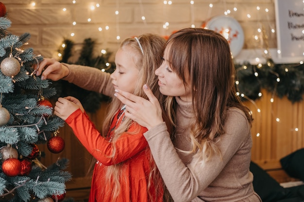 Moeder en dochter versieren samen de kerstboom. Traditioneel ouderschap.