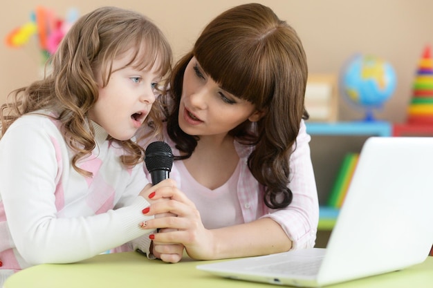 Moeder en dochter zingen aan tafel met laptop