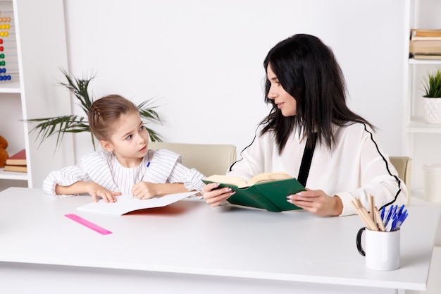 Moeder en dochter zitten aan tafel en doen thuis samen huiswerk.