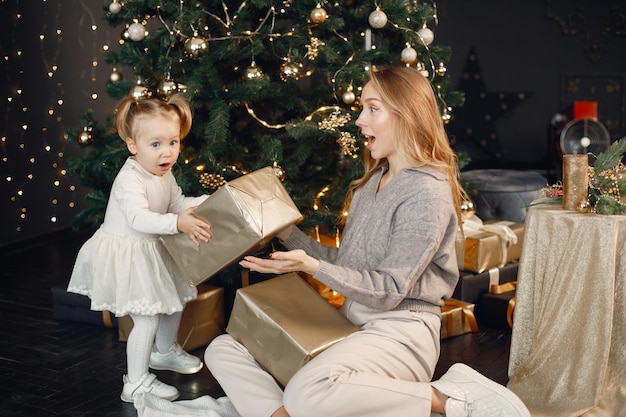 Moeder en dochter zitten bij de kerstboom en houden een cadeau vast