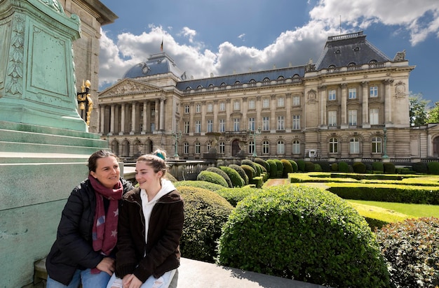 Foto moeder en dochter zitten op de reling tegen een historisch gebouw in de stad.