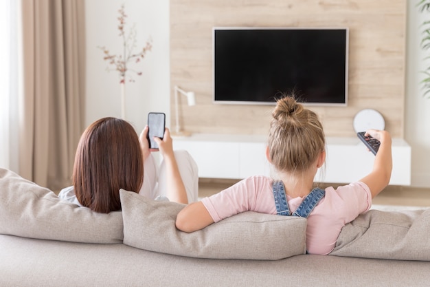 Moeder en dochter zittend op bank tv kijken in de woonkamer