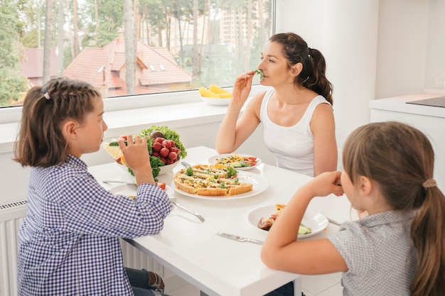 Moeder en dochters die gezond voedsel in keuken eten