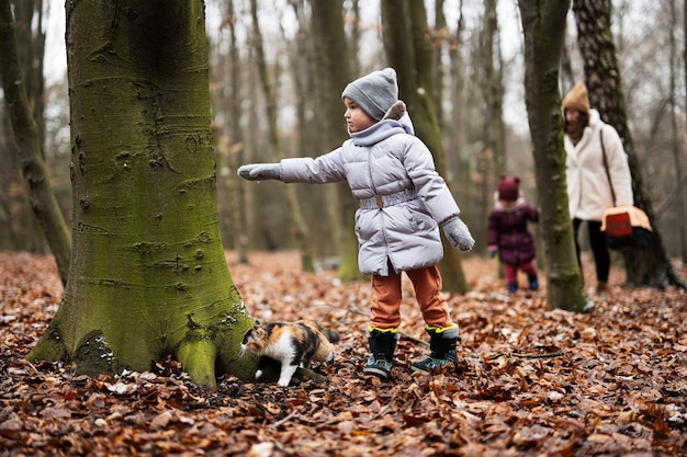 Moeder en dochters die met kat lopen, reizen plastic kooikoets buiten op hout