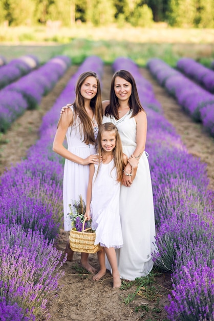 Moeder en dochters in een lavendelveld. Zomerfoto in paarse kleuren.