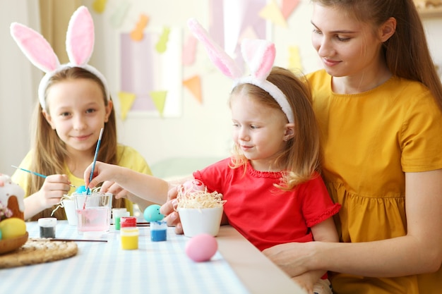 Moeder en dochters schilderen paaseieren voor de paastradities voor de feestdagen