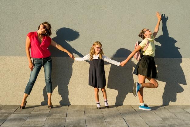 Moeder en dochterstudenten die handen houden gaan naar school