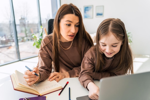 Moeder en dochtertje huiswerk op laptop