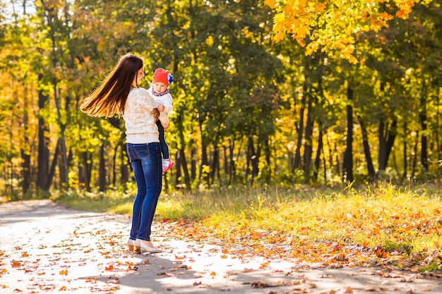 Moeder en dochtertje spelen samen in het herfstpark.