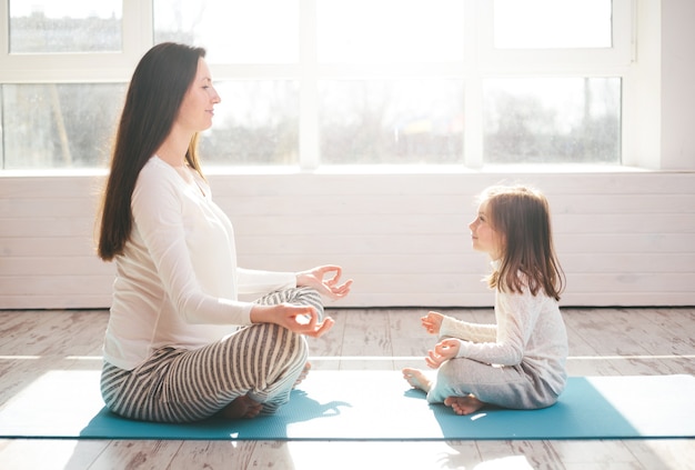 Moeder en een kind gaan thuis yoga