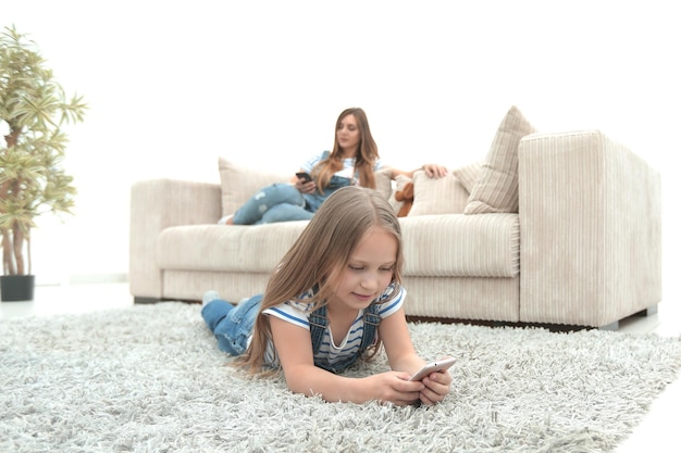 Moeder en haar dochter gebruiken hun smartphones in de nieuwe woonkamerfoto met kopieerruimte