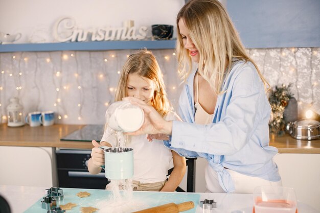 Moeder en haar dochter koken gemberkoekjes voor Kerstmis in de keuken