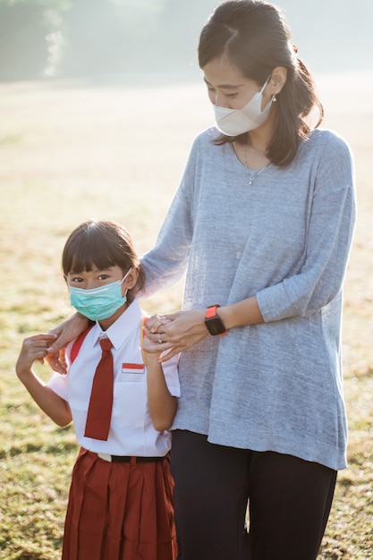 Moeder en haar dochter lopen samen en dragen een gezichtsmasker