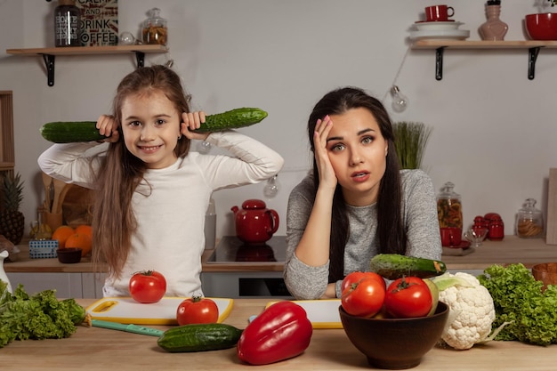 Moeder en haar dochter maken een groentesalade en hebben plezier in de keuken.
