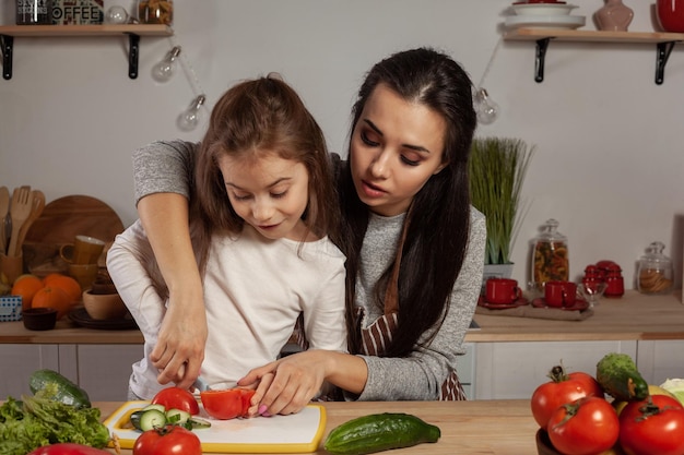 Moeder en haar dochter maken een groentesalade en hebben plezier in de keuken.