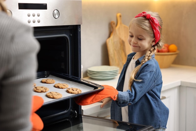 Moeder en haar dochter nemen broodjes uit de oven in de keuken close-up
