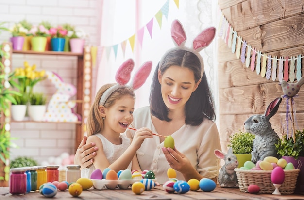 Moeder en haar dochter schilderen eieren Gelukkige familie bereidt zich voor op Pasen