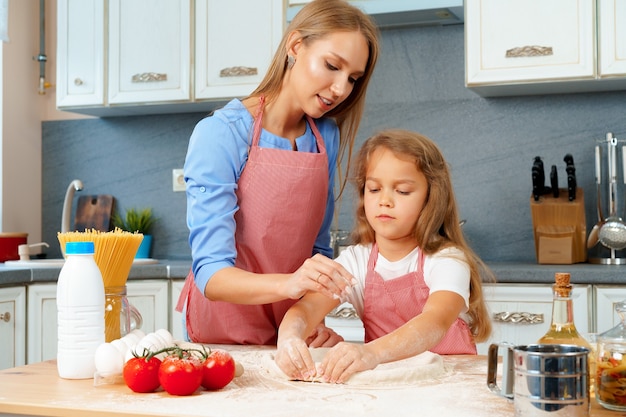 Moeder en haar dochtertje bereiden deeg in de keuken