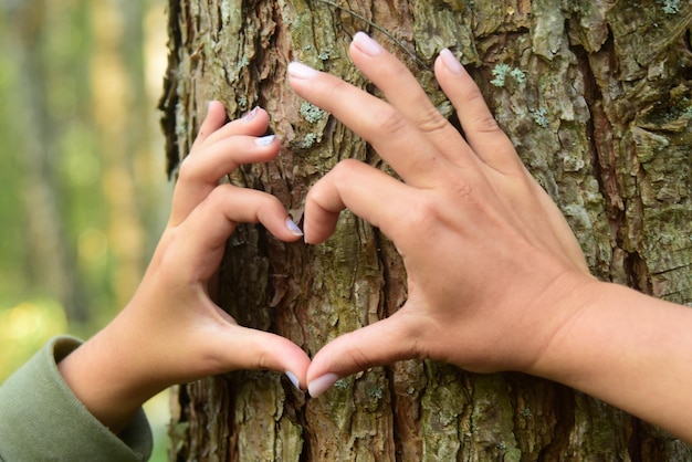 Moeder en haar kind hand in hand in hartvorm framing op boomstam achtergrond natuur