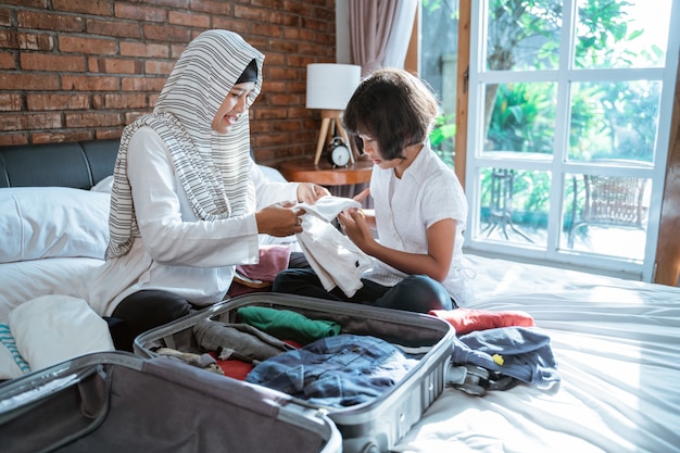 Moeder en haar kind maken kleding klaar en zetten de koffer in om te dragen als ze modderig zijn