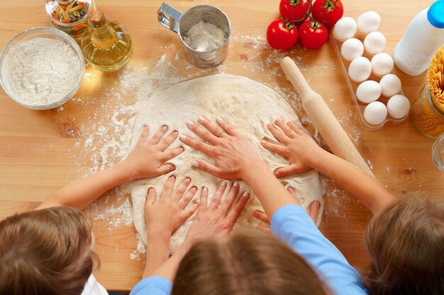 Moeder en haar kinderen deeg kneden op de keukentafel