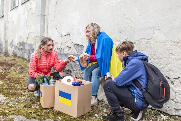 Moeder en haar kinderen delen brood uit een pakket humanitaire hulp dat in Oekraïne is aangekomen