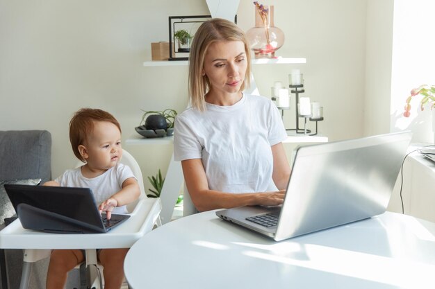 Moeder en haar kleine dochter gebruiken laptops en zitten thuis aan de tafels Moederschapswerk en moederschap