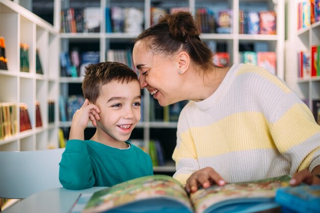 Moeder en haar kleine kind de kleuterzoon lezen samen kinderboeken