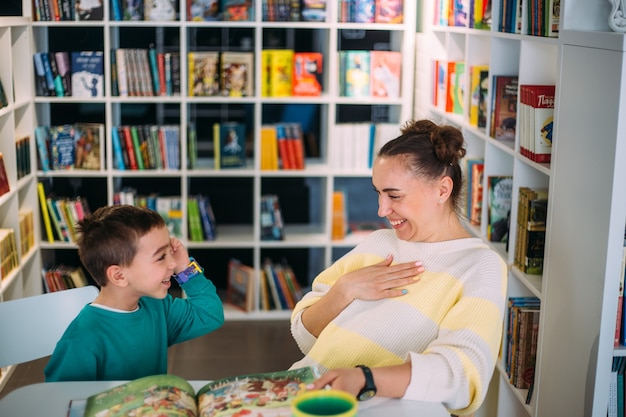 Moeder en haar kleine kind de kleuterzoon lezen samen kinderboeken