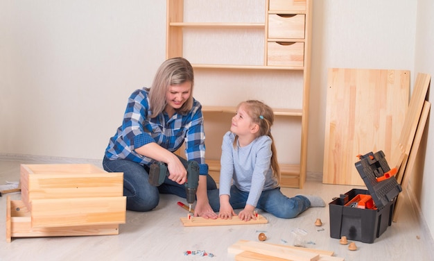 Moeder en haar lachende dochtertje assembleren meubels samen