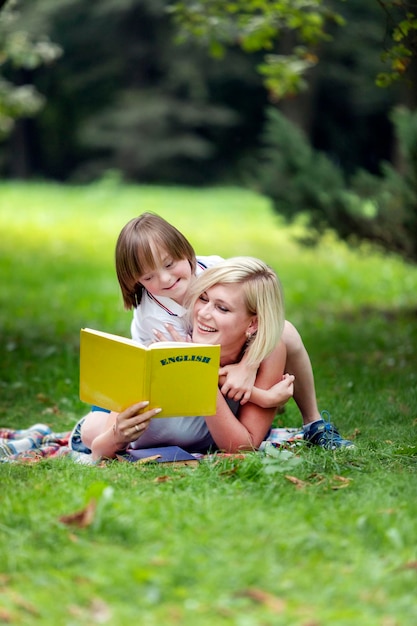 Moeder en haar speciale kind lezen op een kleed te midden van een zomerparkgazon