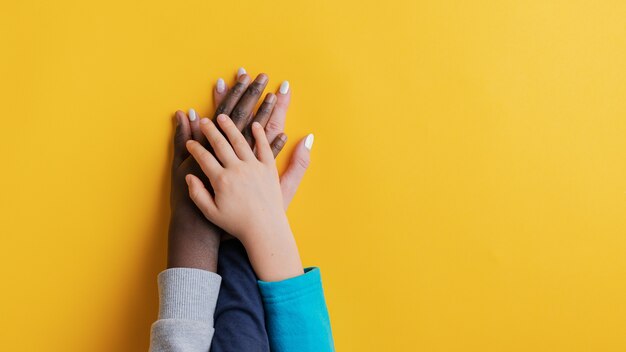 Moeder en haar twee kinderen, één blanke één zwart, stapelen hun handen op