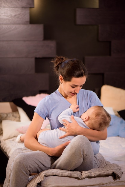 Moeder en haar zoon kind meisje spelen en knuffelen op het bed.