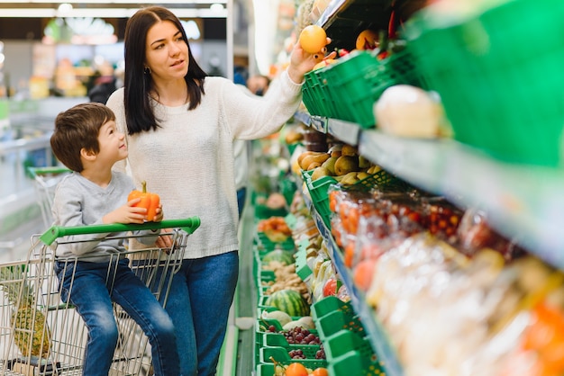 Moeder en haar zoon kopen fruit op een boerenmarkt