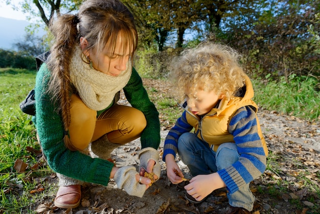 Moeder en haar zoon spelen met herfstbladeren